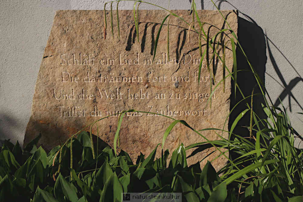 Gedicht in Garamond-Antiqua eingemeisselt auf bruchrauhem Sandstein.